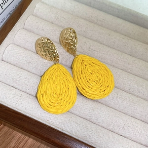 Detail view of mustard yellow drop-shaped woven earrings in a velvet jewelry box