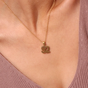 Close-up of number 92 gold pendant necklace in 18K plated finish worn by a model