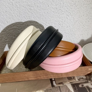Serre-têtes rembourrés en similicuir beige, noir, marron et rose sur un plateau rétro