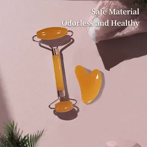 Amber resin face roller and heart-shaped gua sha set on decorative background