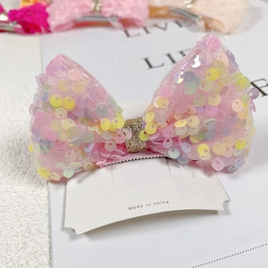 Close-up of pink sequin mermaid bow hair clip with colorful glitters on white card