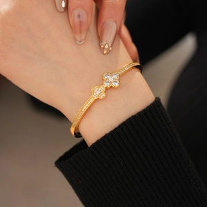 Close-up of a gold-plated clover bangle with zircon pavé on a model's wrist