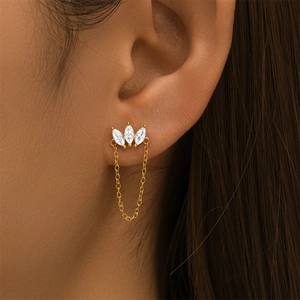 Close-up of golden crown stud earring with marquise gems and delicate chain on ear