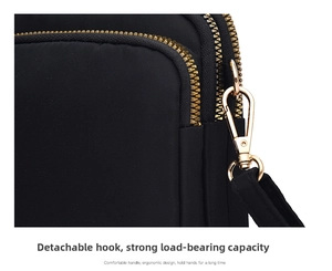 Detail of durable black nylon crossbody bag with gold metal zipper and detachable hook