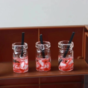 Macro detail of three miniature strawberry resin drink bottles with tiny black straws