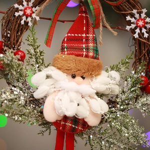 Detail of plush Santa Claus ornament on a rustic rattan wreath with pine needles and berries
