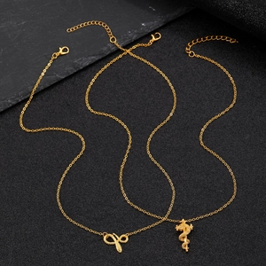 Detailed view of gold snake-shaped and medical staff pendants on a punk style necklace