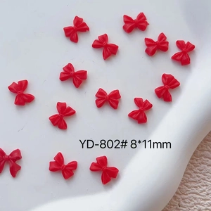 Macro detail of 8x11mm red 3D resin bow nail charms for professional DIY manicure art