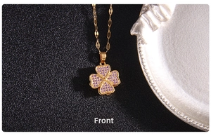 Detail of a rotating golden clover necklace inlaid with sparkling purple zircon crystals