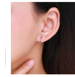 Close-up of a s925 silver rainbow gemstone drop earring worn by a model