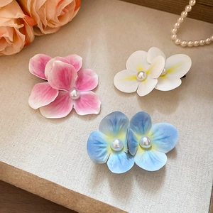 Close-up of floral hair clips with pearls and gradient petals in pink, white, and blue