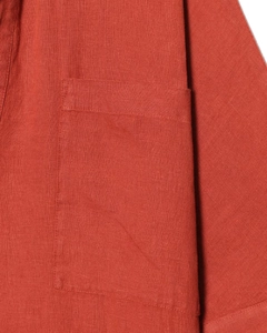 Détail de la texture en lin rouge brique et de la poche plaquée sur la robe chemise