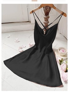 Detail of elegant black silk nightdress with cross-back straps on white wood floor