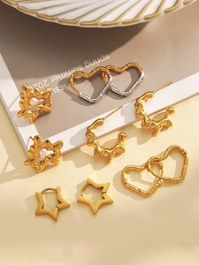 Close-up of golden fashion earring set featuring star, heart, and pearl textures