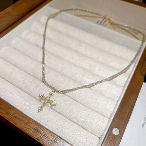 Detail of gold-plated stainless steel cross pendant with crystals on a beaded necklace