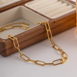 Gros plan d'une chaîne à gros maillons dorés sur un écrin à bijoux en bois
