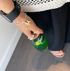 Lifestyle shot of 925 sterling silver rings and balloon dog bracelet with Perrier bottle