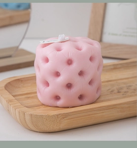 Detailed view of pink quilted texture scented candle on a rustic wooden tray