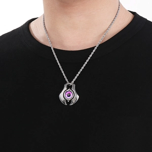 Dettaglio della catena punk argento con ciondolo occhio del male indossata su maglia nera