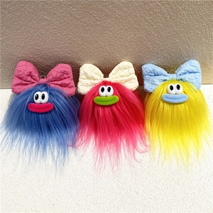 Dettaglio ravvicinato di portachiavi a mostro in peluche colorati con fiocchi