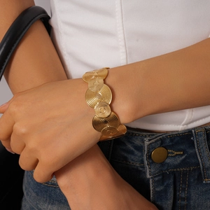 Detail of gold geometric spiral textured circular discs on a minimalist metal cuff bracelet