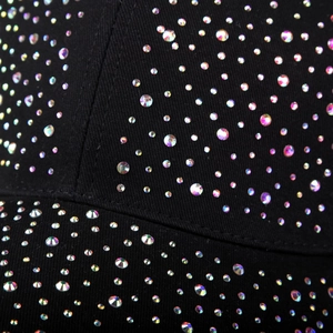 Macro detail of multicolored rhinestones on a black cotton canvas baseball cap surface