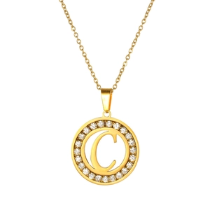 Close-up of gold-plated circular pendant with letter C and sparkling zircon stones