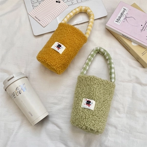 Detailed plush cup carriers in yellow and green with checkered handles and cartoon patches