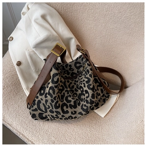 Detailed view of leopard print canvas bag on beige sofa with brown leather shoulder strap