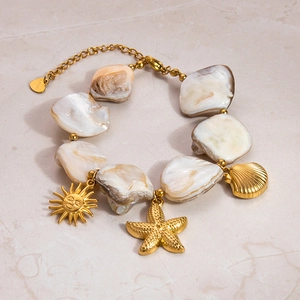 Detailed view of 18k gold stainless steel bracelet with shell beads and ocean charms