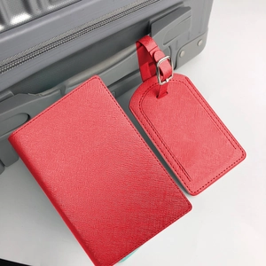 Red Saffiano PU leather passport cover and luggage tag set on grey suitcase