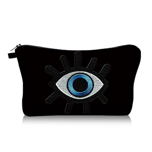 Detailed close-up of the evil eye embroidery on this portable black travel cosmetic bag