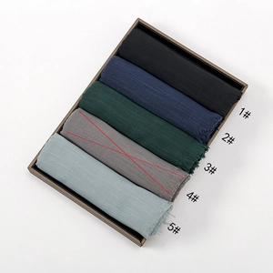 Close-up of assorted solid color slub cotton scarves with fringe details in five neutral tones