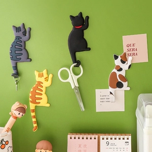 Set of four cute cartoon cat tail magnetic fridge hooks in assorted colors on a green wall