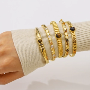 Stack of gold bangles with natural stones and pavé crystals on model's wrist