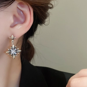 Close-up of vintage silver fleur-de-lis earrings with zircon stones on a model ear