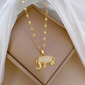 Close-up of golden elephant pendant with crystals on beige box with white silk fabric