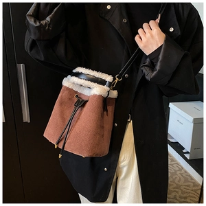 Detail of suede bucket bag featuring faux shearling trim and drawstring closure