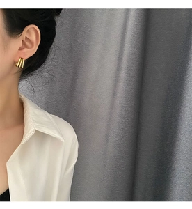 Detailed view of minimalist gold geometric triple-row earrings on a female model