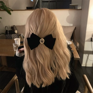 Detail of a vintage black velvet bow hair clip with gold rose emblem on blonde hair