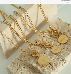 Macro detail of golden layered chain necklace with a Beloved engraved round pendant