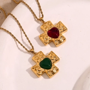Detail of 18K gold plated hammered cross pendants with heart-shaped red and green gems