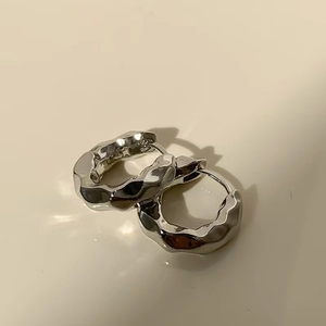 Macro detail of silver geometric earrings with irregular liquid lava texture finish