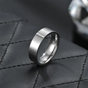 Macro shot of brushed finish 6mm titanium steel band ring on a black leather background