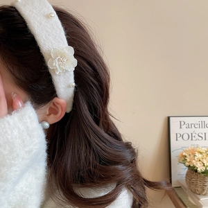 Close-up of plush white floral headband with elegant pearls on a female model