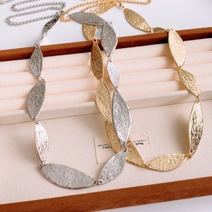 Detailed macro view of gold and silver leaf-shaped chain with hammered metal texture