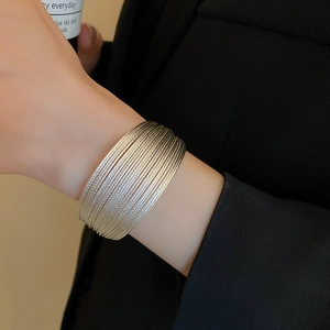Primo piano di bracciali multistrato argento sovrapposti con finitura testurizzata