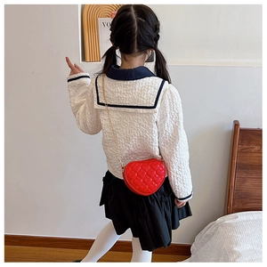 Detailed view of red heart-shaped quilted bag with gold chain strap on a child