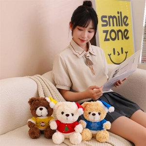 Three Christmas teddy bears in colorful shirts sitting on a cozy sofa next to a person