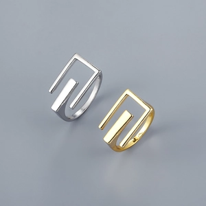 Detailed close-up of square open rings in gold and silver finish with geometric design